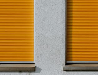 Zwei Fenster mit orangefarbenen Rollläden: Rollladen reinigen lassen: innen, außen und im Obergeschoss